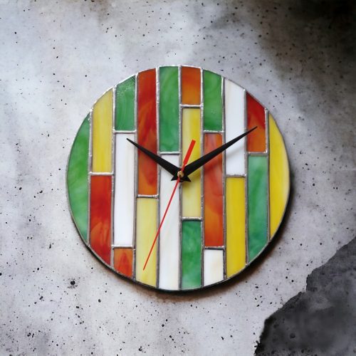 Vidám és színes geometrikus mintákkal díszített üveg falióra, mely frissességet és életteliséget sugároz